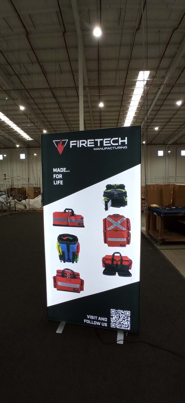 A tall FireTech Manufacturing display image featuring six emergency equipment bags, branding, and a QR code.